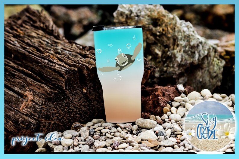 May include: A turquoise and peach ombre tumbler with a graphic of a sea turtle swimming in the ocean. The tumbler is sitting on a bed of small white rocks.