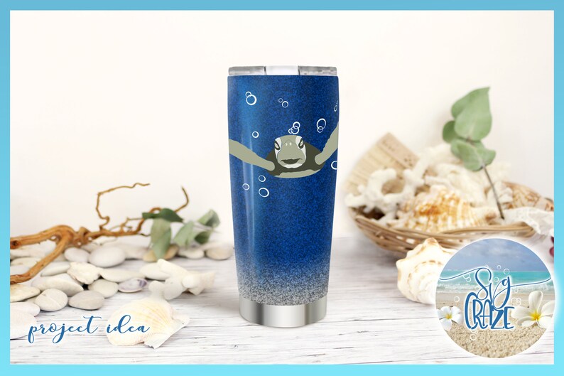 May include: A blue and silver stainless steel tumbler with a sea turtle design and bubbles. The tumbler is sitting on a white wooden surface with seashells and a sign that says "Sea Craze".