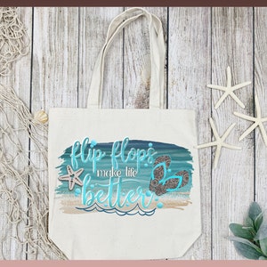 May include: A white canvas tote bag with a blue and green watercolor design featuring the text "flip flops make life better" and a pair of flip flops. The bag is on a wooden surface with a starfish and a piece of fishing net.