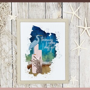 May include: A watercolor painting of a blue heron standing on a stack of pink candles with the text "The beach is calling I must go" in white. The background is a blue and green watercolor wash.