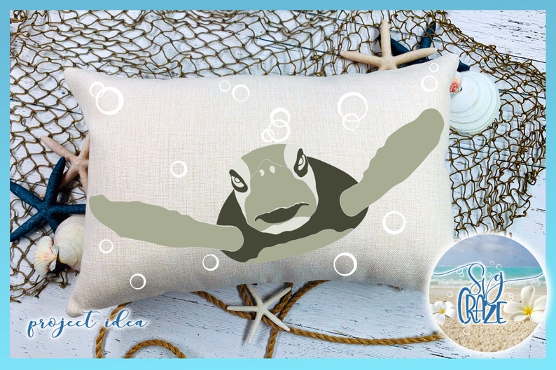 May include: A beige pillow with a green sea turtle design. The turtle is swimming upwards with its head and flippers visible. White circles are scattered around the turtle, representing bubbles.