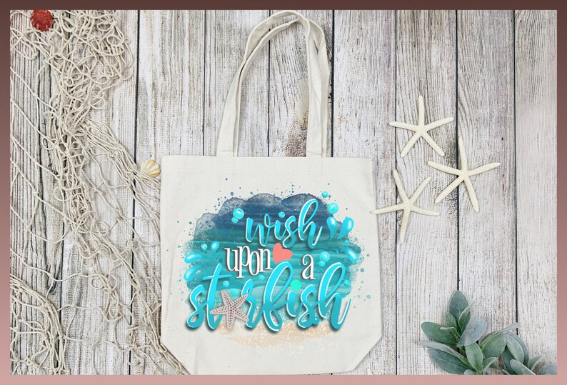 May include: A white canvas tote bag with a blue and green watercolor design of ocean waves and a starfish. The text "wish upon a starfish" is written in blue and green lettering.