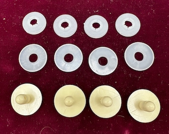May include: Ten white plastic buttons with a small hole in the center. The buttons are arranged in two rows of five.