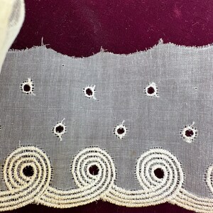May include: White eyelet lace trim with a scalloped edge and a repeating pattern of circles. The lace is delicate and has a vintage feel.