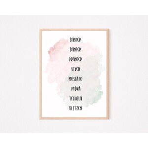 May include: A framed print with a watercolor background in shades of pink and green. The print features a list of names, including Dasher, Dancer, Prancer, Vixen, Moscato, Vodka, Tequila, and Blitzen.