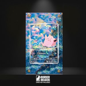 May include: A framed Pokémon trading card featuring a pink Clefairy character with Japanese text. The card is set against a colorful background of clouds and flowers. The frame is clear with gold-colored corner accents. The bottom of the frame has the text "BORDER BREAKERS CARD NOT INCLUDED."