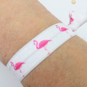 May include: White elastic hair tie with a pink flamingo print.
