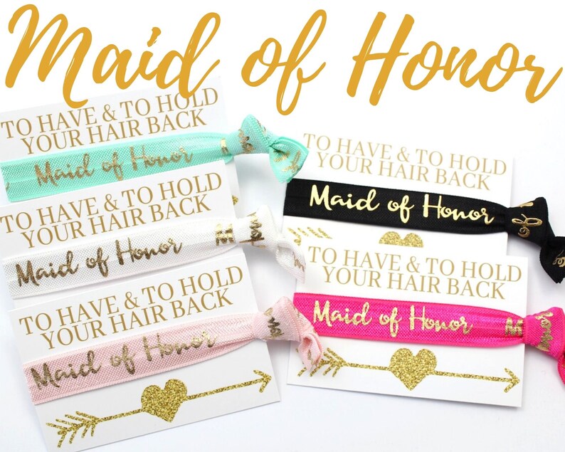 May include: Set of five hair ties with the text "Maid of Honor" and the phrase "To Have & To Hold Your Hair Back" printed on them. The hair ties are in various colors, including pink, black, white, and green.