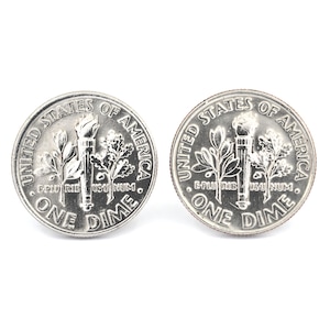 Könnte beinhalten: Zwei silberne US-Dimes. Jede Münze trägt die Aufschrift "UNITED STATES OF AMERICA" und "ONE DIME" am Rand. Die Mitte jeder Münze zeigt eine Fackel, einen Olivenzweig und einen Eichenzweig.