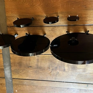 Peut inclure: Cinq &eacute;tag&egrave;res circulaires noires mont&eacute;es sur un mur en bois. Les &eacute;tag&egrave;res sont de tailles diff&eacute;rentes et sont toutes en mat&eacute;riau brillant.
