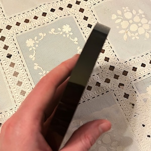 Peut inclure: Un objet noir, rectangulaire et brillant avec des bords arrondis. L'objet est tenu dans une main.