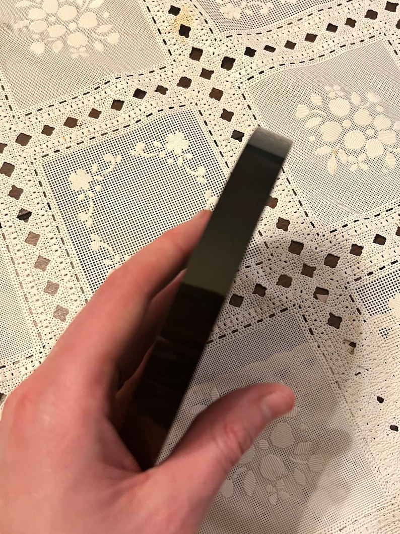 Peut inclure: Un objet noir, rectangulaire et brillant avec des bords arrondis. L'objet est tenu dans une main.