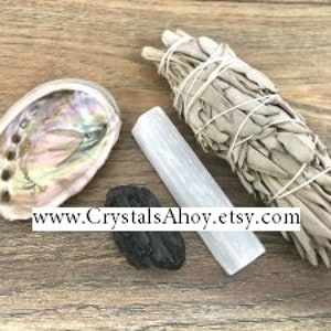 May include: A smudging kit with white sage, a white selenite crystal, a black obsidian stone, and an abalone shell.