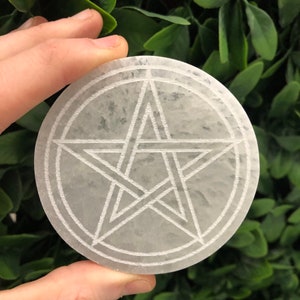 May include: A white selenite charging plate with a pentagram etched into the surface.