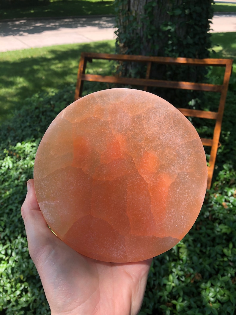 May include: A round, orange-colored, translucent, salt plate with a rough, textured surface.