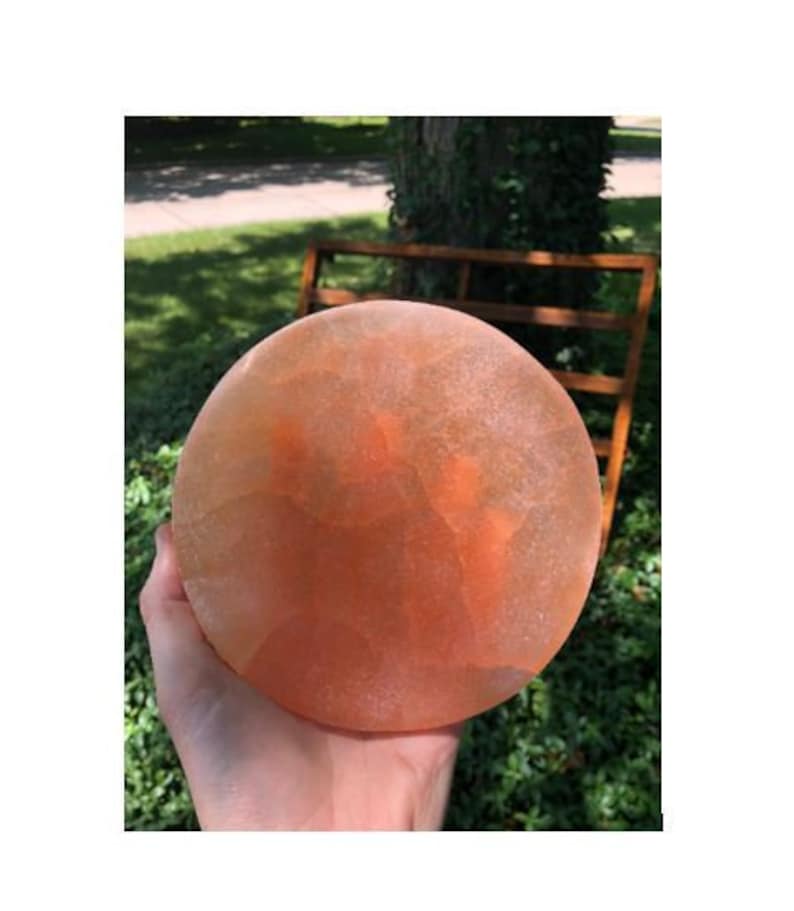 May include: A large, round, orange-colored Himalayan salt lamp with a textured surface.