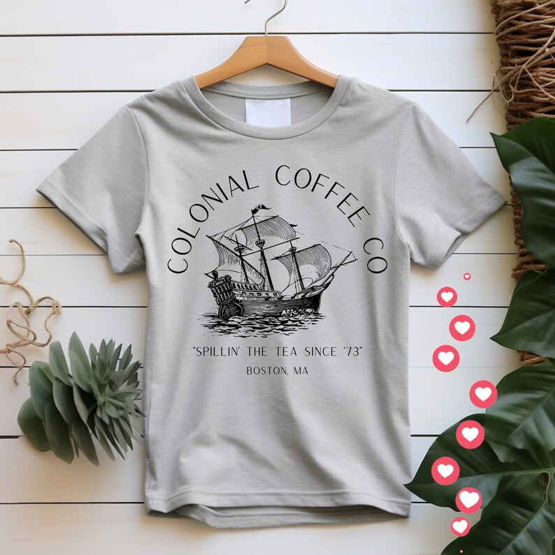 May include: A light gray t-shirt with the words "COLONIAL COFFEE CO" arched above a black and white illustration of a tall ship. Below the ship, the text reads "'SPILLIN' THE TEA SINCE '73" and "BOSTON, MA."