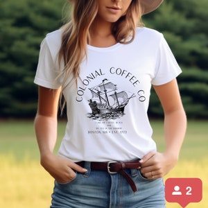 May include: White t-shirt with a black graphic of a sailing ship and the text "COLONIAL COFFEE CO." Below the ship is the text "I LIKE MY COFFEE BLACK AND MY TEA IN THE HARBOR BOSTON, MA &bull; EST. 1773."