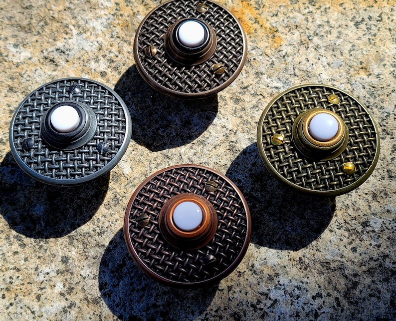 May include: Four round doorbells with a mesh design and a white button in the center. The doorbells have different metal finishes: silver, bronze, copper, and brass. Small screws are visible around the edges.