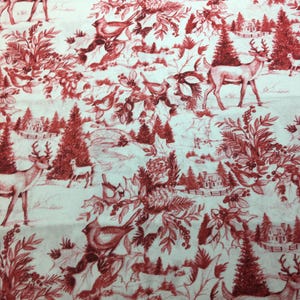 May include: A white fabric featuring a repeating toile pattern in deep red ink. The design depicts winter scenes with deer, small birds, pine trees, holly branches with berries, and small houses scattered across the surface in a continuous print.