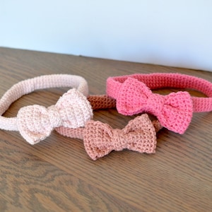 May include: Three crocheted headbands with bows in different shades of pink. The headbands are made of a soft, stretchy yarn and are perfect for adding a touch of color to any outfit.
