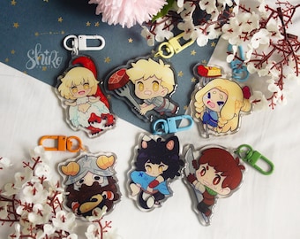 May include: Collection of acrylic keychains featuring cartoon characters with various designs. Each keychain has a different character with unique outfits and accessories, and a colored clasp. The keychains are displayed on a white surface with floral accents.