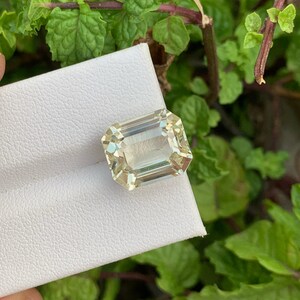 Pode incluir: Uma gema verde clara com um corte esmeralda retangular. A gema est&aacute; sobre um fundo branco.