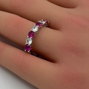 May include: A silver band ring with alternating pink and white round gemstones.
