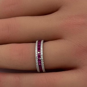 Könnte beinhalten: Ein Weißgold-Bandring mit einer Reihe von rosafarbenen Saphiren und einer Reihe von Diamanten.