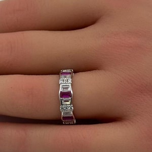 May include: A silver band ring with alternating pink and white rectangular stones.