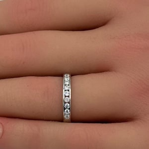 May include: A thin silver band with a row of small, clear diamonds set in a pave setting.