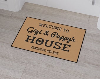 May include: A brown doormat with the text "Welcome to Gigi & Pappy's House Admission: One Hug" in black lettering.