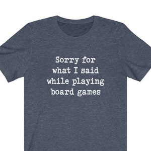 May include: A dark blue t-shirt with the text "Sorry for what I said while playing board games" in white.