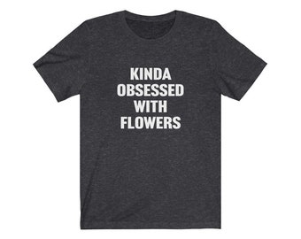 May include: A dark heather grey t-shirt with the text "Kinda obsessed with flowers" printed in white.