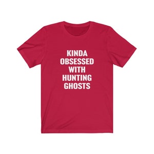 May include: Red short-sleeved t-shirt with white text that reads "Kinda obsessed with hunting ghosts".