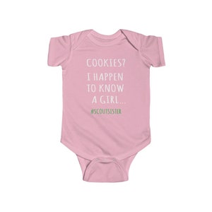 May include: Pink baby onesie with white text that reads "COOKIES? I HAPPEN TO KNOW A GIRL... #SCOUTSISTER"