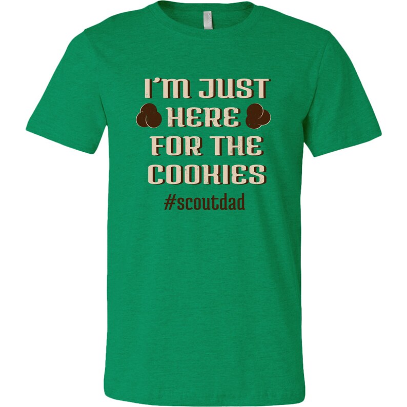 May include: Green t-shirt with the text "I'm just here for the cookies #scoutdad" in brown and beige text.