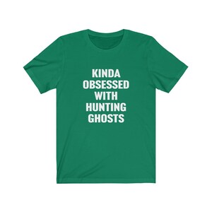 May include: A green t-shirt with white text that reads "Kinda obsessed with hunting ghosts".