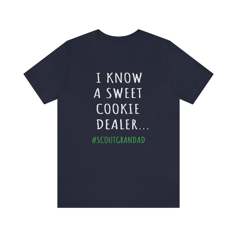 Op de afbeelding: Donkerblauw T-shirt met witte tekst die luidt "Ik ken een zoete koekjesdealer... #ScoutGrandad".