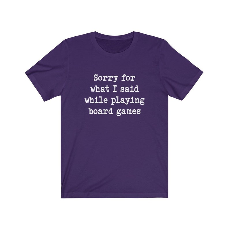 May include: Purple short-sleeved t-shirt with white text that reads "Sorry for what I said while playing board games".