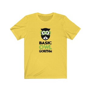 Puede incluir: Camiseta amarilla de manga corta con un b&uacute;ho negro y verde con gafas y el texto "BASIC OWL GORITHM".