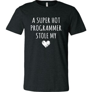 Pu&ograve; includere: Una maglietta grigia scura melange con il testo "A super hot programmer stole my" e un grafico a forma di cuore bianco.