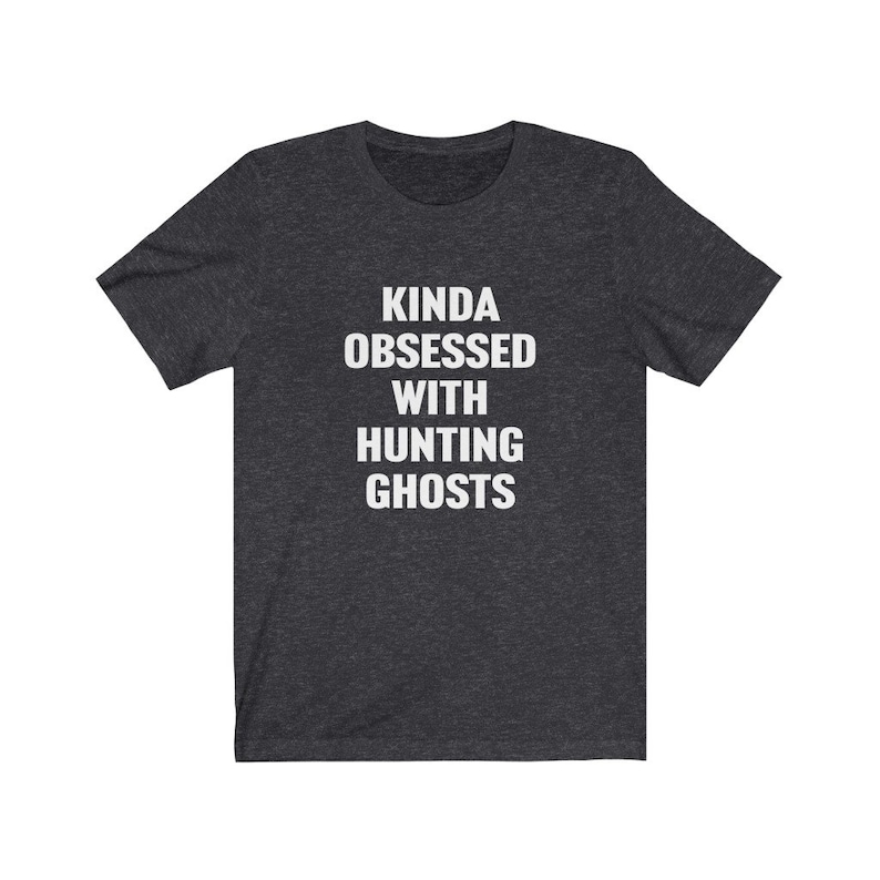 May include: A dark heather grey t-shirt with the text "Kinda obsessed with hunting ghosts" printed in white.