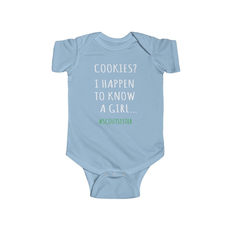 May include: Light blue baby onesie with white text that reads "COOKIES? I HAPPEN TO KNOW A GIRL... #SCOUTSISTER".