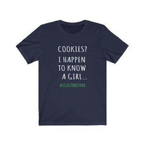 May include: Navy blue t-shirt with white text that reads "COOKIES? I HAPPEN TO KNOW A GIRL... #SCOUTBROTHER".