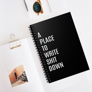 May include: A black spiral bound notebook with the text "A PLACE TO WRITE SHIT DOWN" in white.