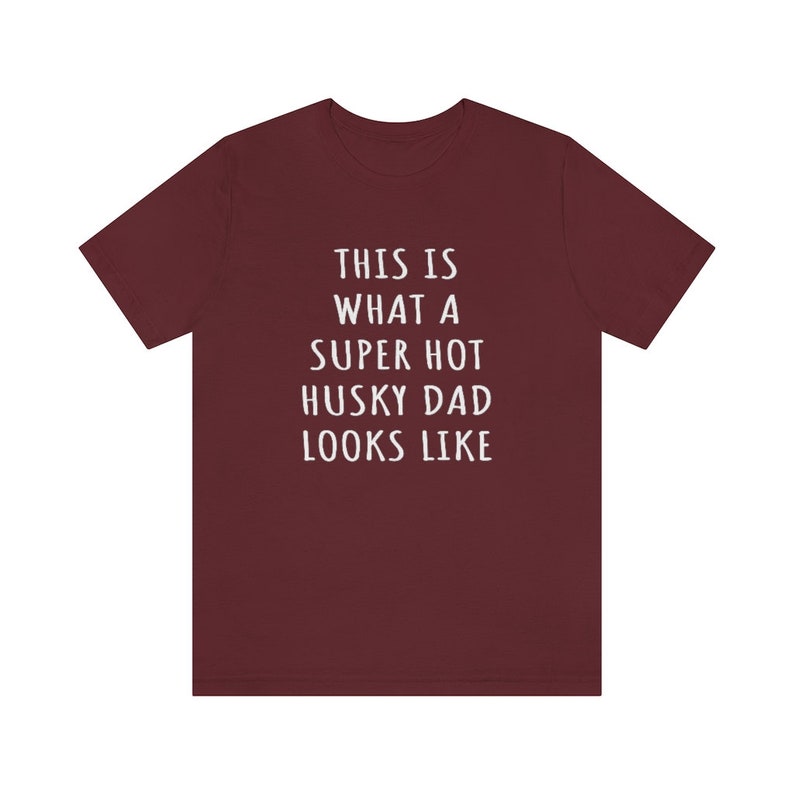 May include: A maroon t-shirt with white text that reads "This is what a super hot husky dad looks like."