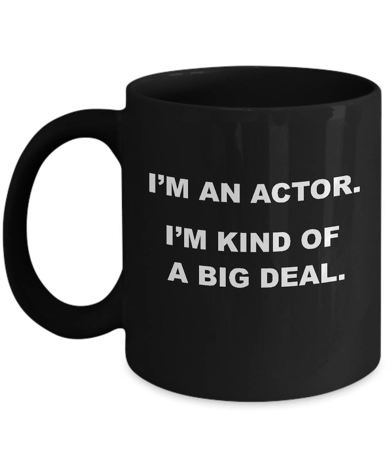 May include: A black ceramic mug with a white handle. The mug has the text "I'M AN ACTOR. I'M KIND OF A BIG DEAL." printed in white, centered on the mug. The mug is designed for hot beverages.