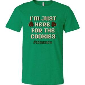 May include: Green t-shirt with the text "I'm just here for the cookies #scoutmom" in brown text.