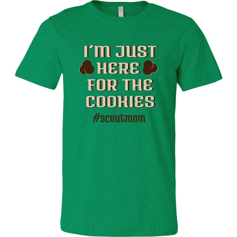 May include: Green t-shirt with the text "I'm just here for the cookies #scoutmom" in brown text.